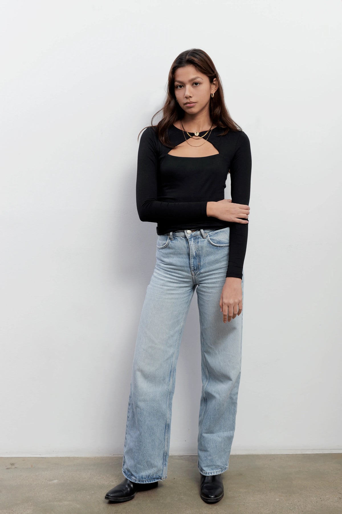 Model wearing an elegant long sleeves black top with a triangle cut-out and a golden button closure. The top is made with Tencel™Modal fabric.