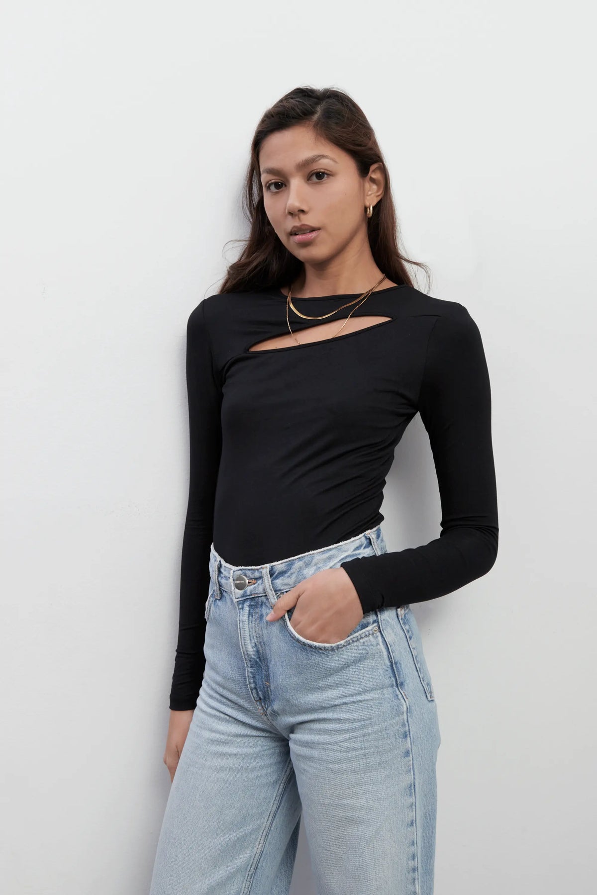 Model wearing an everyday long sleeves black top with a diagonal cut-out shape made with Tencel™Modal fabric