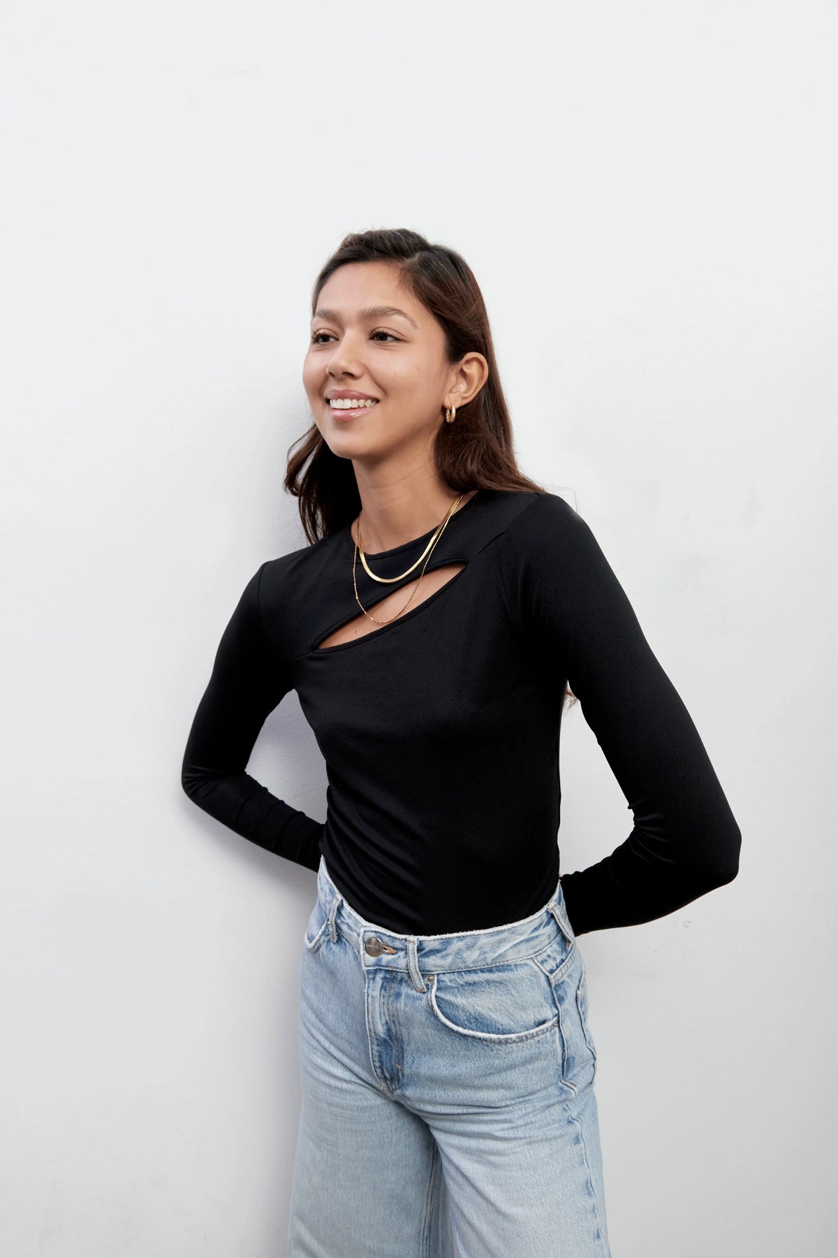 Model smiling and wearing an everyday black top with a diagonal cut-out shape made with Tencel™Modal fabric