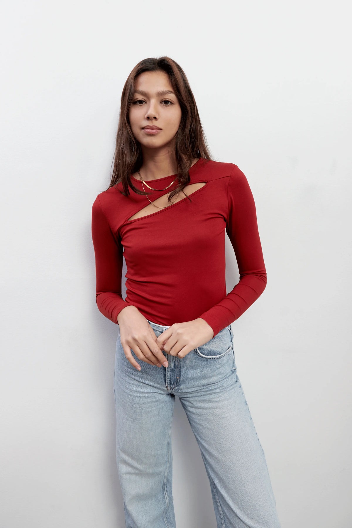 Model wearing an everyday long sleeves red top with a diagonal cut-out shape made with Tencel™Modal fabric