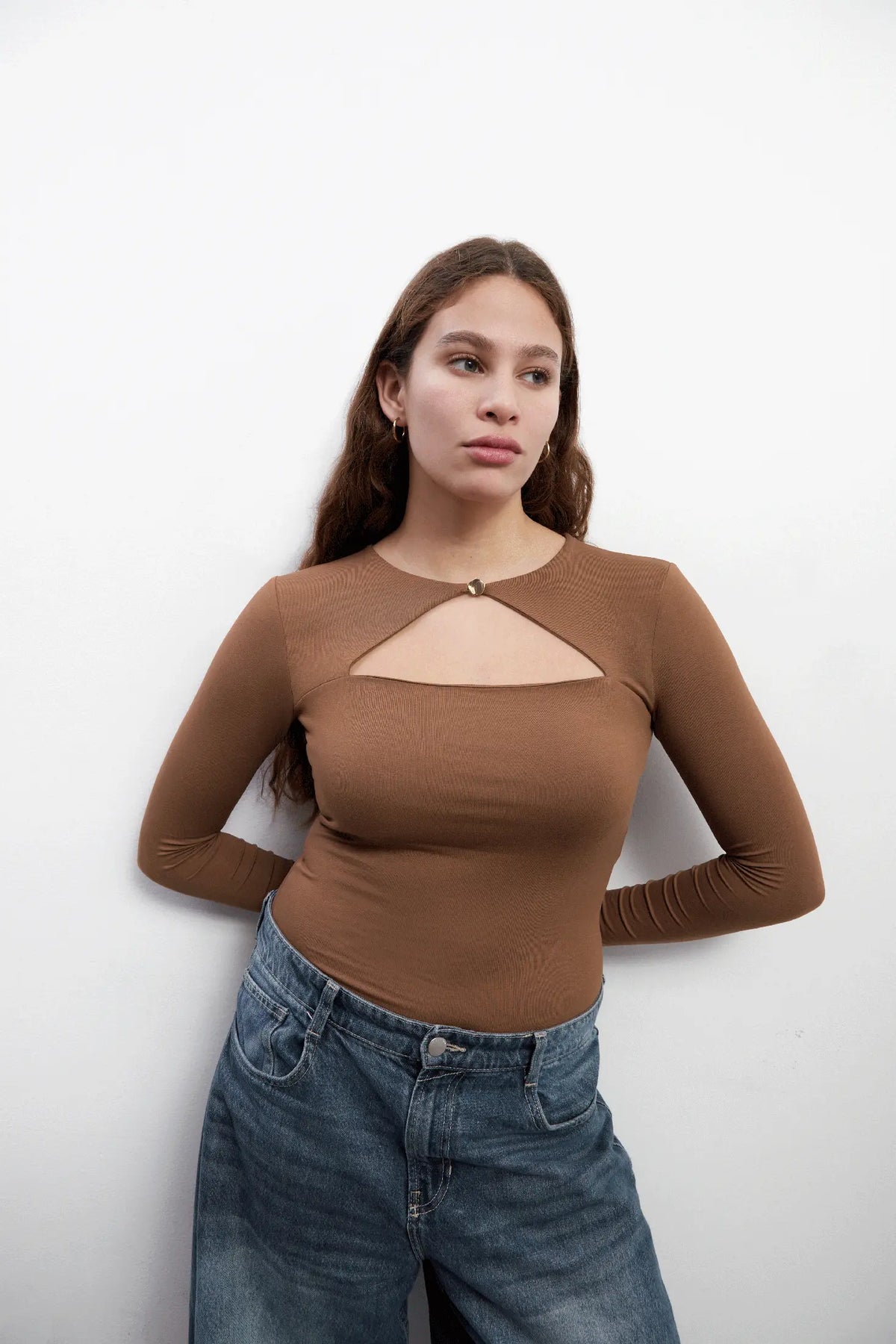 Model wearing an elegant long sleeves brown top with a triangle cut-out and a golden button closure. The top is made with Tencel™Modal fabric.